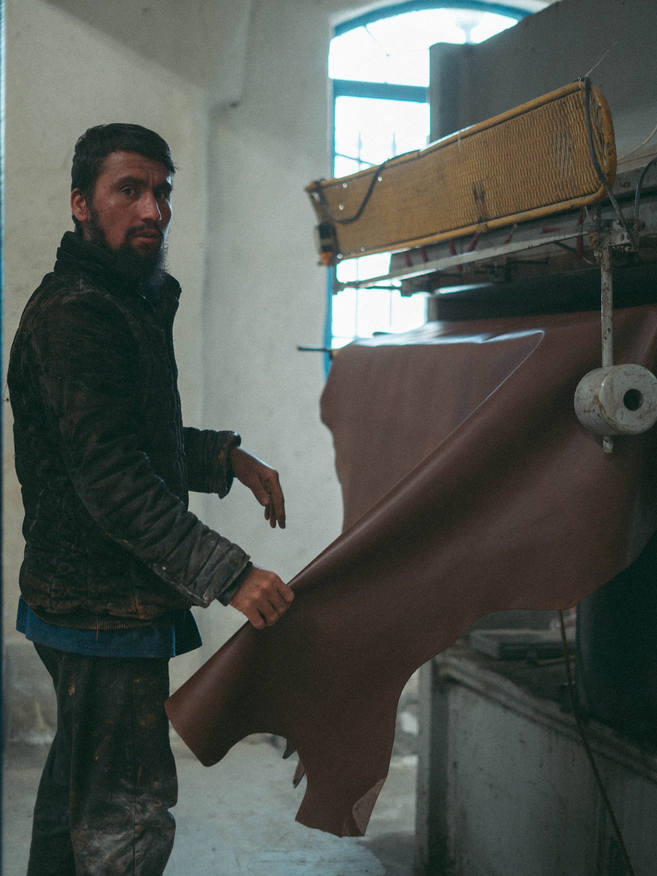 A craftsman working with a large piece of leather in a workshop; illustrative stock photograph