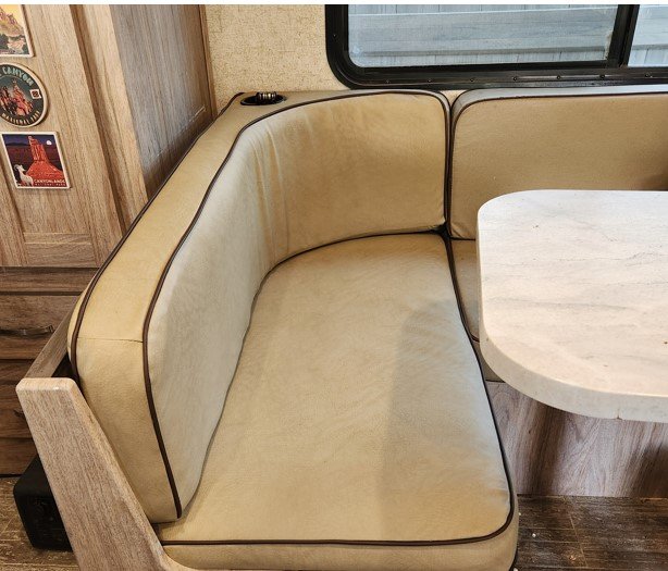 Cream upholstered cushions fitted around a table in a compact interior