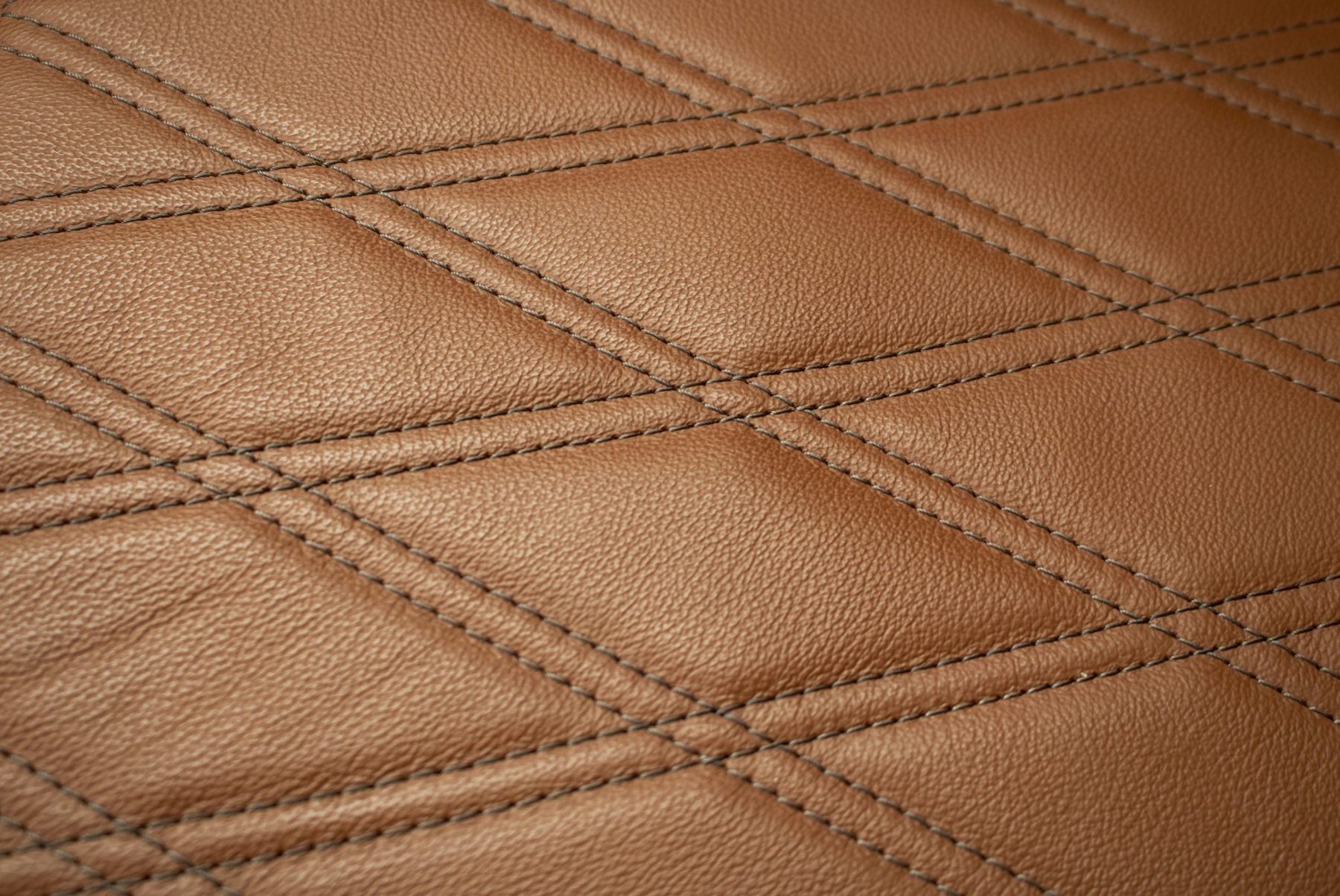 Close photograph of quilted brown leather by James Lee; illustrative stock material reference